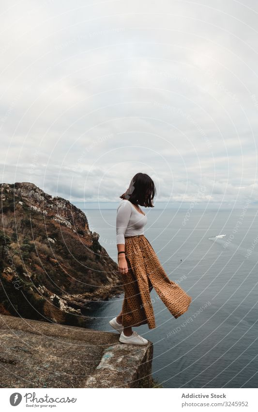 Lonely woman standing on cliff against seascape with cloudy sky coast height freedom water balance viewpoint highland danger fresh female solitude decision