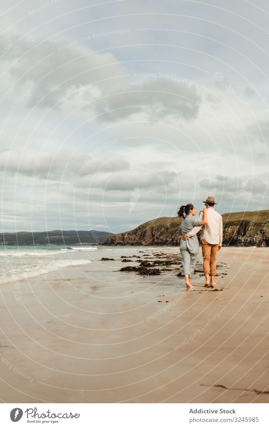 Happy couple having fun on Scottish coast beach sandy rock scotland scottish cloudy together happy enjoy holding summer travel tourism nature adventure vacation