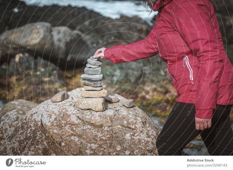 Tourist balancing stones during travel in rocks tourist balance pyramid woman building equilibrium cairn landscape cliff scenic connection nature old ancient