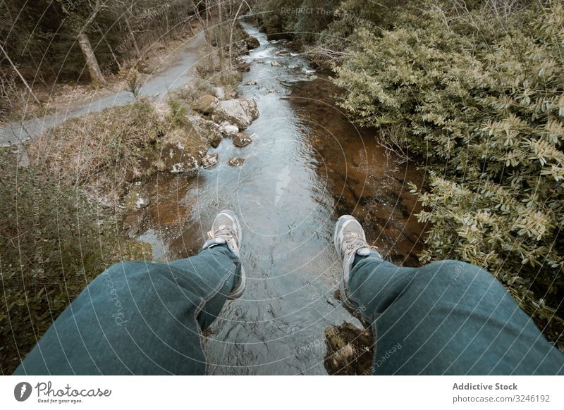 Tourist sitting on bridge and dangling legs over river tourist hang forest ireland park tollymore hiker person active walk nature landscape stream scenic