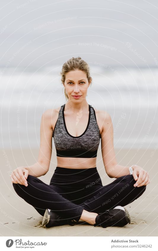 Woman meditating on the beach woman yoga practice sea ocean female exercise balance training workout young athlete active calm tranquility sportswear body