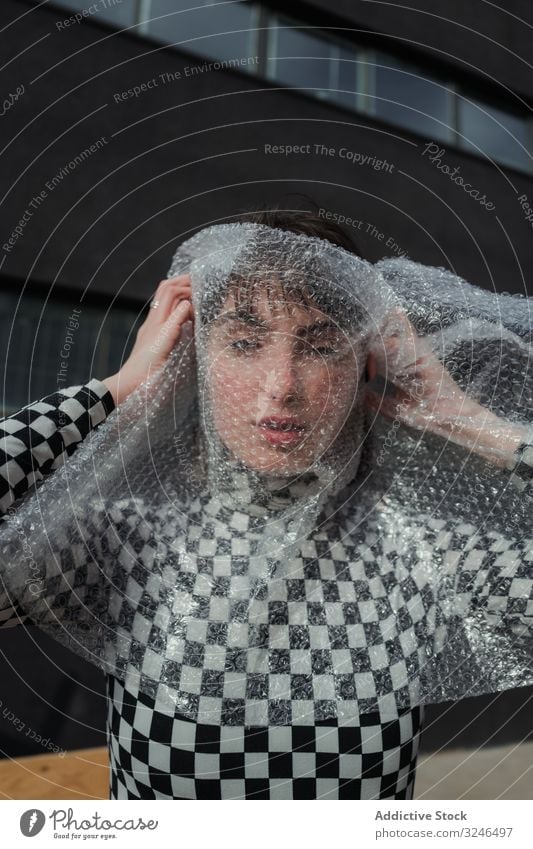 Fashionable woman in trendy casual wear in bubble wrap at city street fashion stylish teenager female hipster wrapping hidden outfit model beauty young vogue