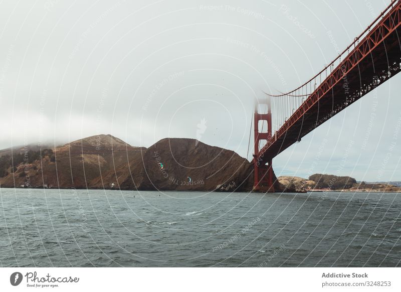 Red bridge construction over wavy dark water shore structure architecture rocky landscape stone sea mountain ocean travel island nature golden gate