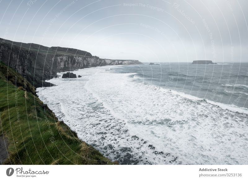 Northern Ireland coastline with waves ocean seascape stormy cloudy rock grass foam northern ireland landscape weather cold grey season power energy mountain