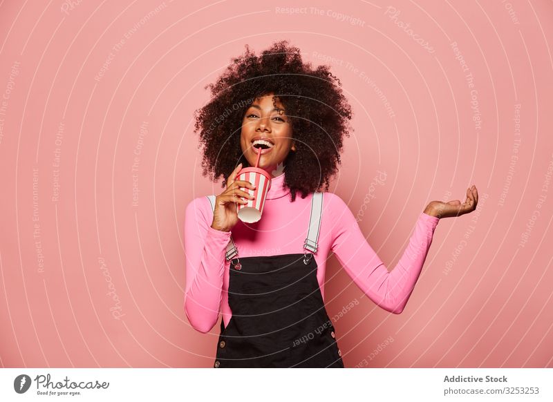 Happy black woman with disposable cup of drink standing against pink background happy straw african american laugh cheerful gesture ethnic female young casual