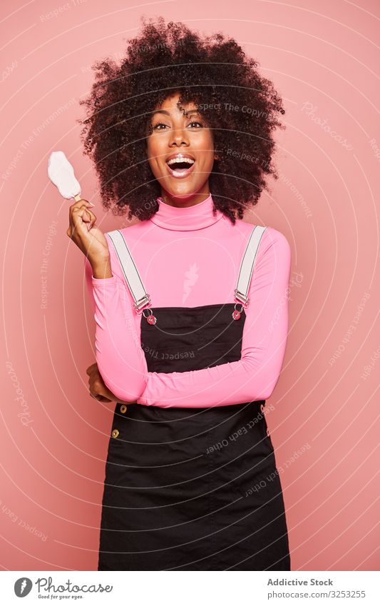 Funny woman with ice cream on stick looking at camera fun happy smeared lips pink laugh cheerful excited eating african american black stand ethnic female young