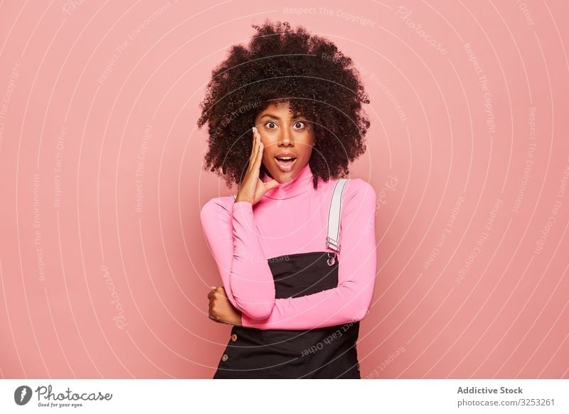 Shocked African American woman looking at camera surprised amazed shocked young casual pink african american black stand female ethnic turtleneck overall