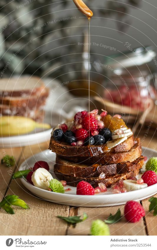 Honey pouring over fried toasts with fruit honey stack spill table mint breakfast morning food dessert snack treat portion sauce sweet calorie dish tasty