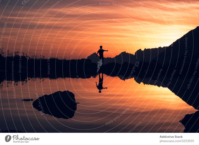 Person standing on shore and reflecting in water silhouette lake mountain reflection picturesque tranquil seaside stone sunset surface mirror landscape scenic