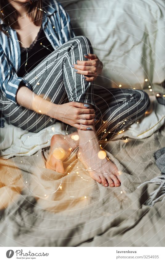 Woman sitting in her bed with Christmas fairy lights Evening Cozy Feasts & Celebrations Public Holiday Faceless pajamas Christmas & Advent hygge Fairy lights