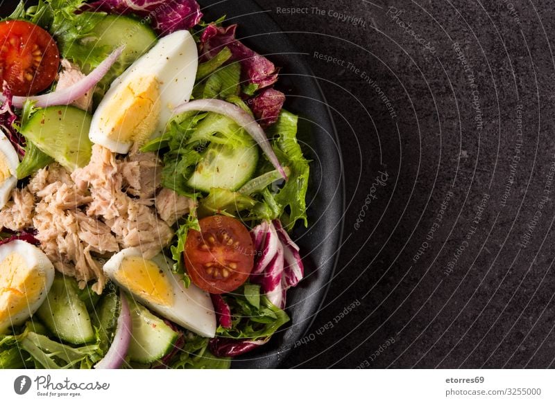 Salad with tuna, egg and vegetables on black background Vegetable Tuna fish Egg Tomato Lettuce Black Plate Onion Cucumber Slice Mixed Olive oil Healthy Eating