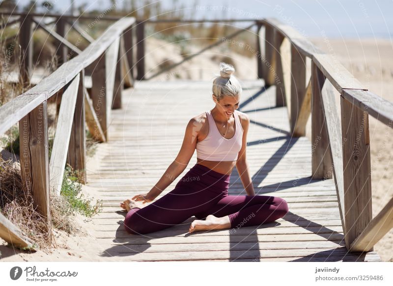 Meditation By Sex Young Women In White Dress On A Bridge By The Sea. Pretty  Woman Doing Yoga On The Beach. Sporty Woman Sitting In Yoga Position At Sea  View Background. Stock