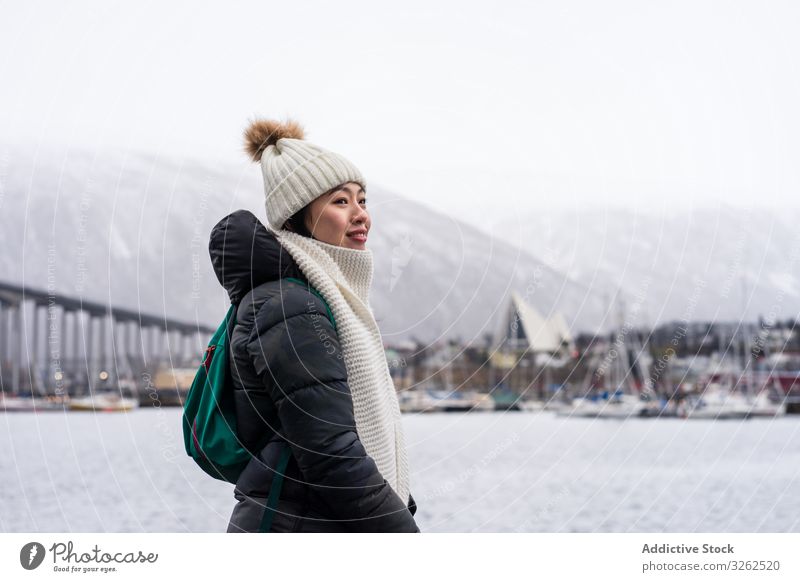 Asian female tourist in warm wear at snowy field near city tourism walking winter woman clothing travel building town holiday asian sightseeing skyline relaxing