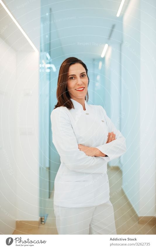 Confident dentist in white uniform with crossed arms looking at camera doctor smiling confident dental clinic medical medicine hygiene dentistry visit hospital