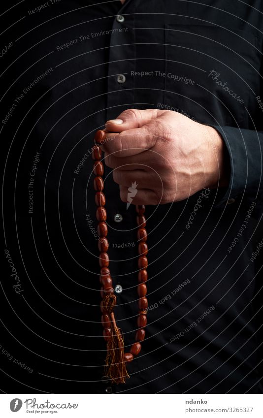man in a black shirt holds a brown stone rosary Meditation Human being Man Adults Arm Hand Fingers Culture Brown Black Trust Hope Religion and faith handle