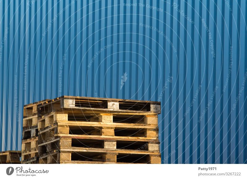 Pallet stacks in front of blue metal wall Warehouse Wall (barrier) Wall (building) Logistics Palett Wood Metal Business Competition Symmetry Colour photo
