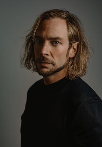 serious Elegant Young man Youth (Young adults) T-shirt Blonde Long-haired Facial hair Looking Authentic Dark Natural Rebellious Power Calm Pride Identity