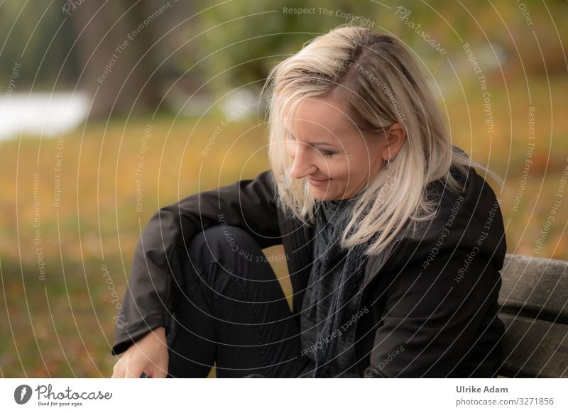 Woman sitting relaxed on a bench with a smile on her face and reading - UT Hamburg Face of a woman smilingly Blonde blonde hair Long-haired black clothes Soft