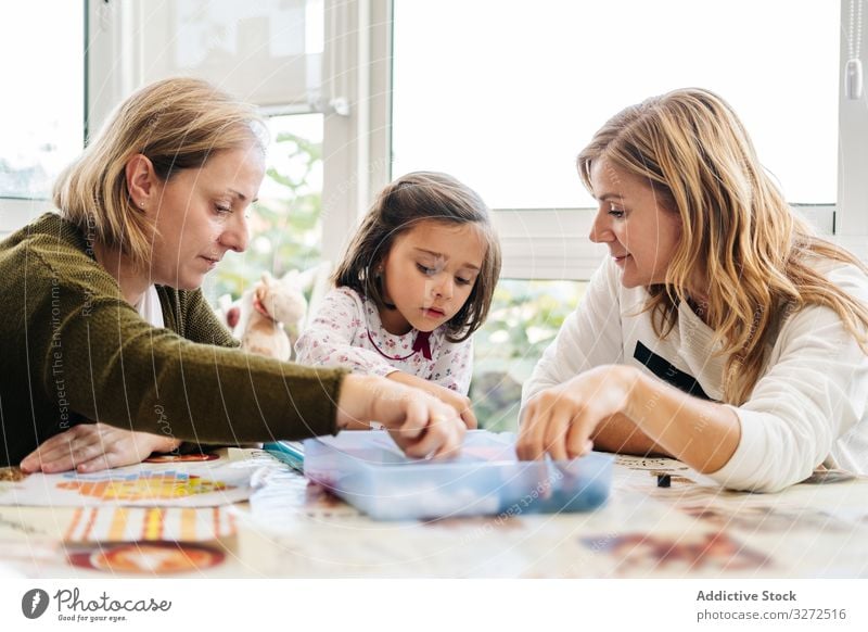 Woman playing board game with daughter and granddaughter family multi generational mother daughters together fun happy grandmother woman girl table piece female