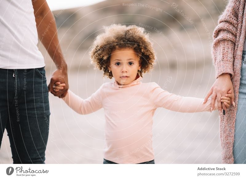 Stylish multiethnic family walking on nature hold hands together parent toddler smile happy stroll cheerful lifestyle modern child man bonding love tender