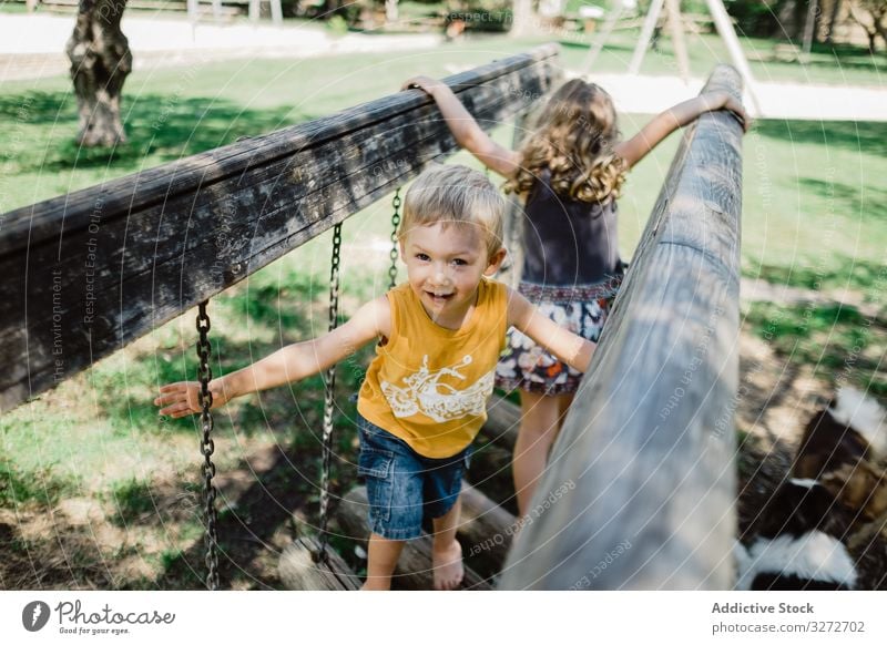 Funny children climbing on playground in summer day adventure having fun playful meadow siblings tree childhood nature bridge park active lawn girl boy