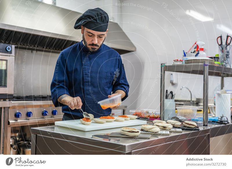 Male cook preparing snacks in kitchen chef work sandwich red caviar gourmet counter man prepare uniform hat professional occupation male ethnic food restaurant