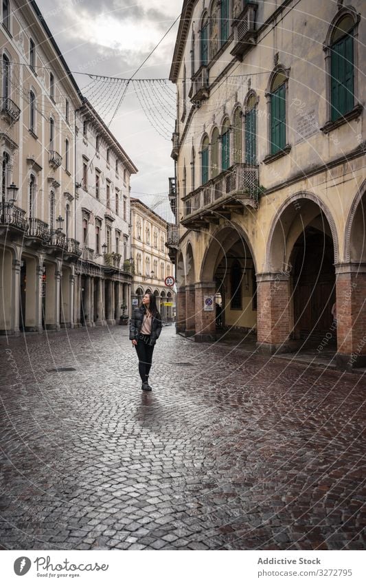 Curious female tourist strolling at old city street on overcast weather tourism walking ancient aged curious explore architecture building journey vacation