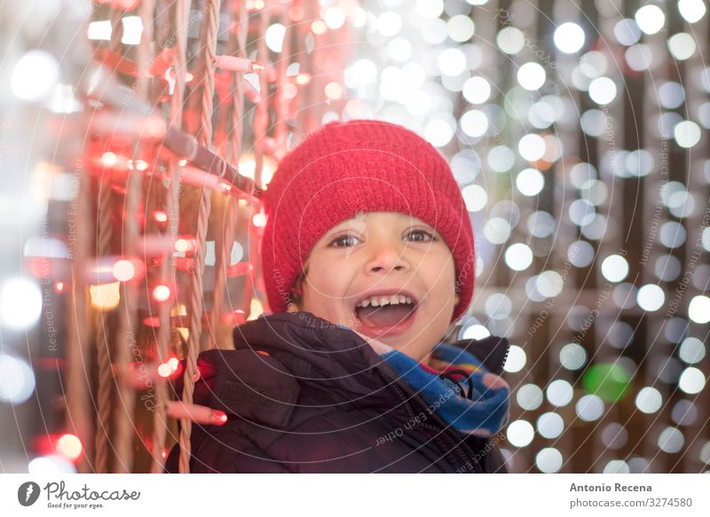 Smiling boy in christmas night looking at camera Joy Winter Feasts & Celebrations Child Human being Boy (child) Scarf Hat White Emotions Surprise holidays cold