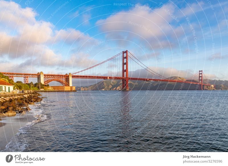 View of Golden Gate Bridge along the coastline in San Francisco Vacation & Travel Tourism Ocean Nature Sky Coast Skyline Monument Metal Historic Blue Red