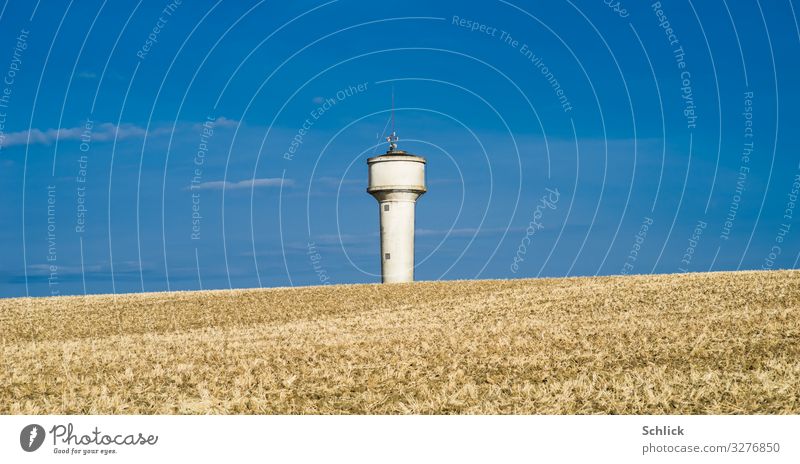 Dry farmland in front of blue sky and water tower Environment Water Summer Climate change Field Tower Blue Brown White Change Water tower acre Agriculture