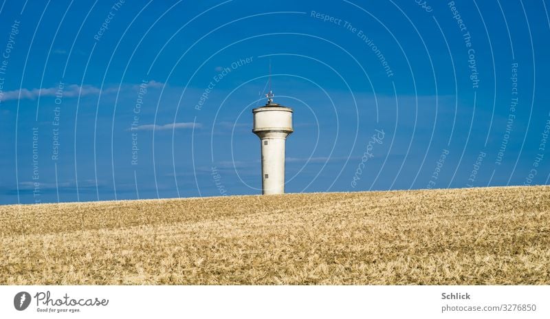 Dry farmland in front of blue sky and water tower Environment Water Summer Climate change Field Tower Blue Brown White Change Water tower acre Agriculture