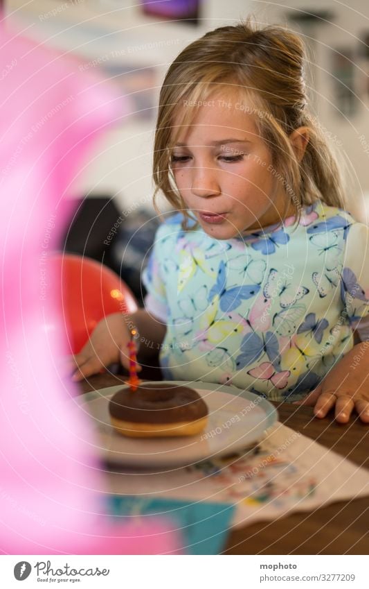 Girl in a dress blows out candle on doughnut First day at school celebration shoulder stand girl School Schoolchild blow out Blow First class first school day