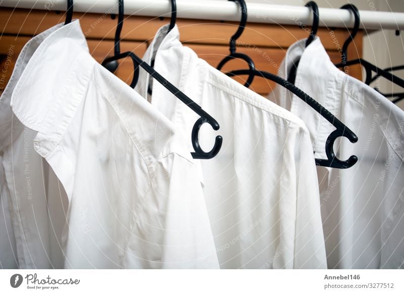 Row of white cotton clothes hang on black hangers on a rack Shopping Style Design Office Business Woman Adults Man Fashion Clothing T-shirt Shirt Dress