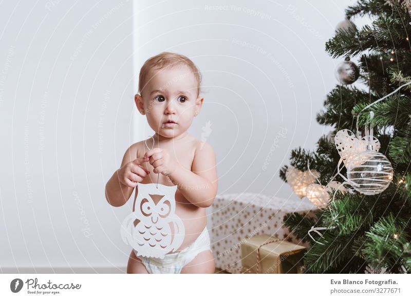 cute baby girl wearing diaper decorating Christmas Tree - a