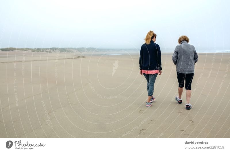 Back view of women walking on beach Lifestyle Calm Beach Human being Woman Adults Mother Grandmother Family & Relations Sand Sky Autumn Fog Sneakers Footprint
