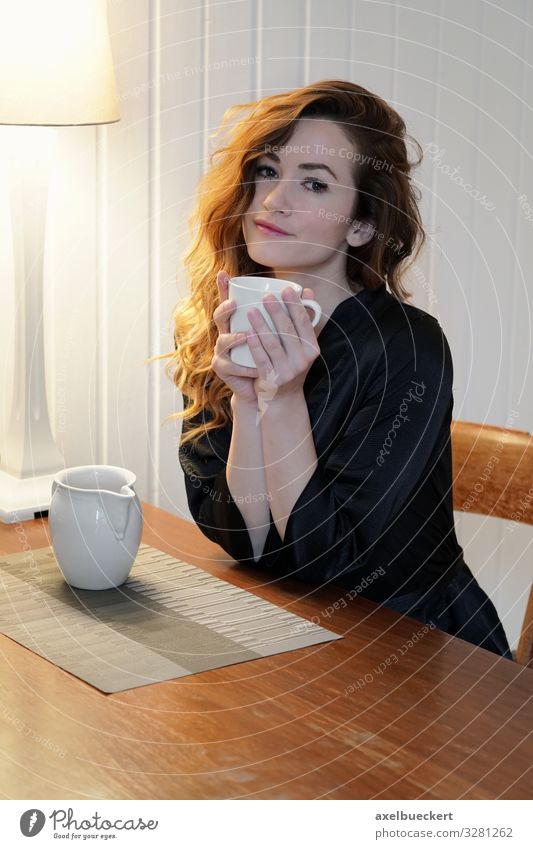 young woman with coffee at the kitchen table Beverage Drinking Hot drink Milk Coffee Tea Cup Mug Lifestyle Beautiful Well-being Contentment Calm