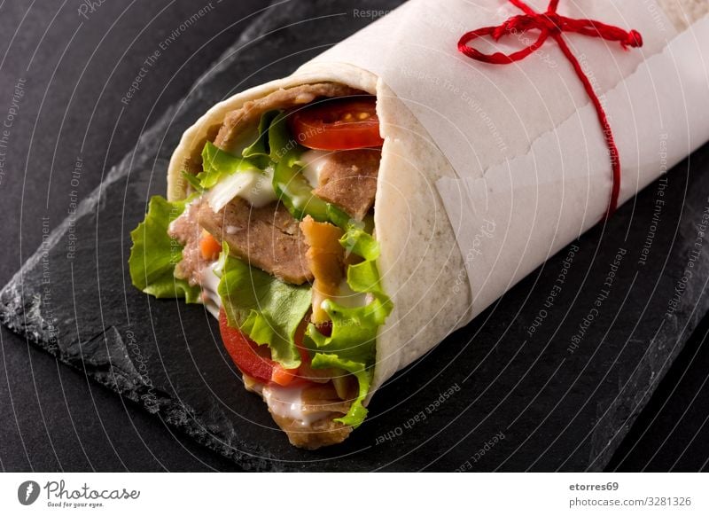 Doner kebab or shawarma sandwich on black slate background doner Kebab Sandwich Wrap Meat Roll Chicken Vegetable Tomato Lettuce Onion Herbs and spices Sauce