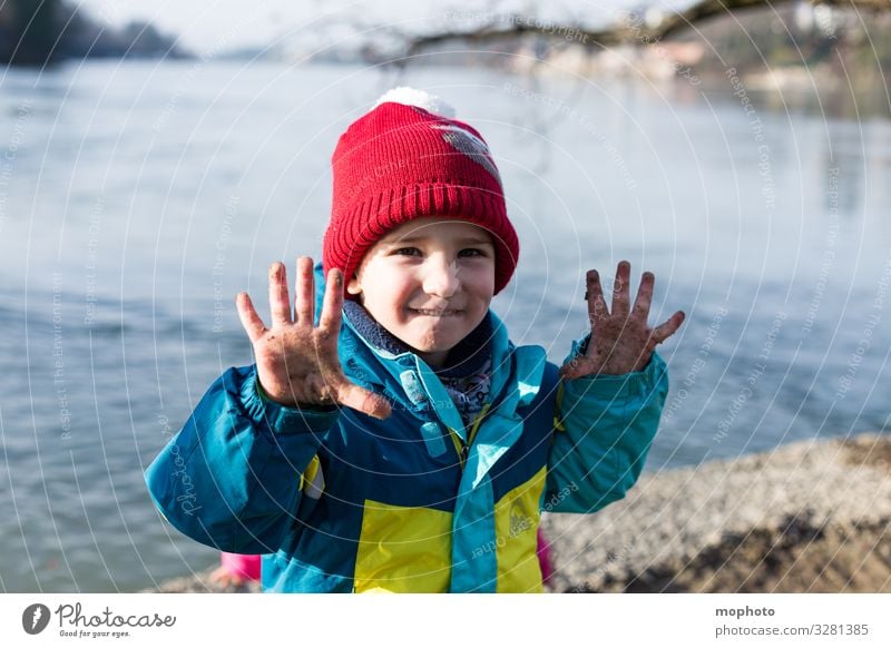 Boy with dirty fingers on water Nature variegated out filth Dirty experience Fingers by hand hands Jacket Boy (child) chill Child cap natural Rhine Red frowzy