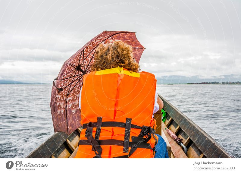 female tourist in water taxi at Inle lake Clouds Weather Rain Transport Taxi Safety Inle Lake Asia life vest umbrella Vest Colour photo