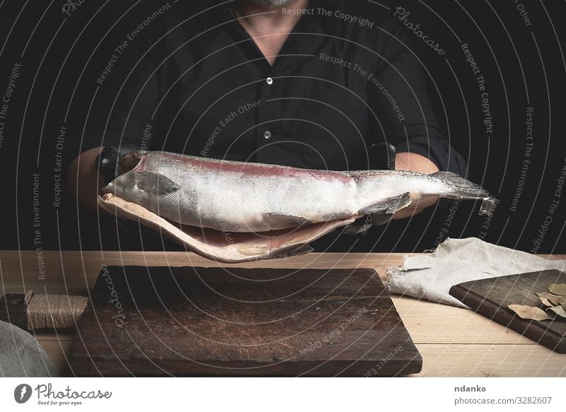 headless salmon fish Meat Fish Seafood Nutrition Dinner Table Kitchen Tool Man Adults Hand Gloves Wood Fresh Large Brown Black board Caucasian chef cook cooking