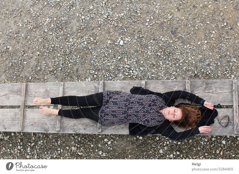 a clothed woman with dark and patterned clothing lies with closed eyes on a jetty Human being Feminine Woman Adults 1 45 - 60 years Environment Nature Spring