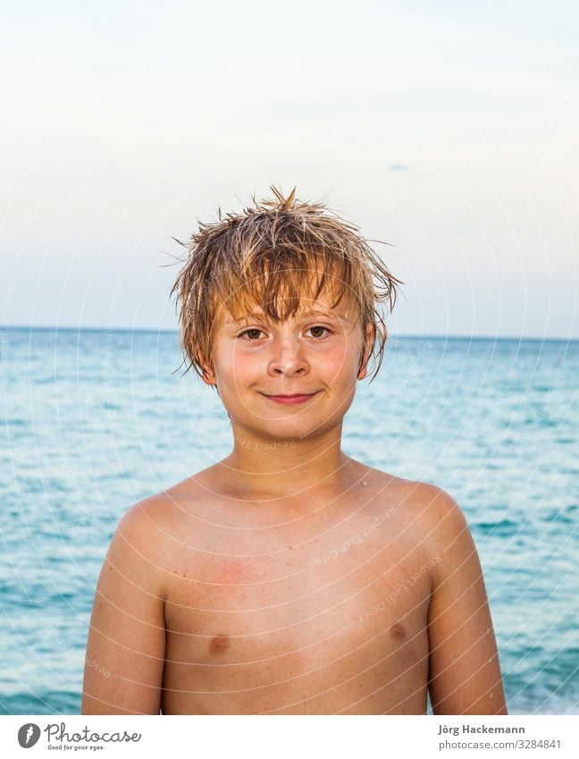 portrait of cute smiling boy at the beach under blue sky - a Royalty ...