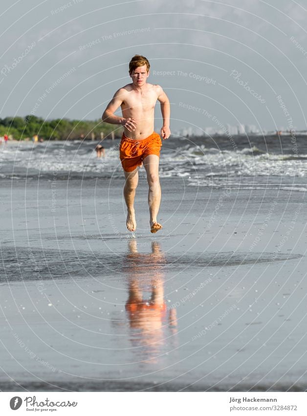 teenager enjoys jogging along the beach Joy Happy Body Vacation & Travel Beach Jogging Boy (child) Youth (Young adults) Sand Movement Fitness To enjoy Smiling