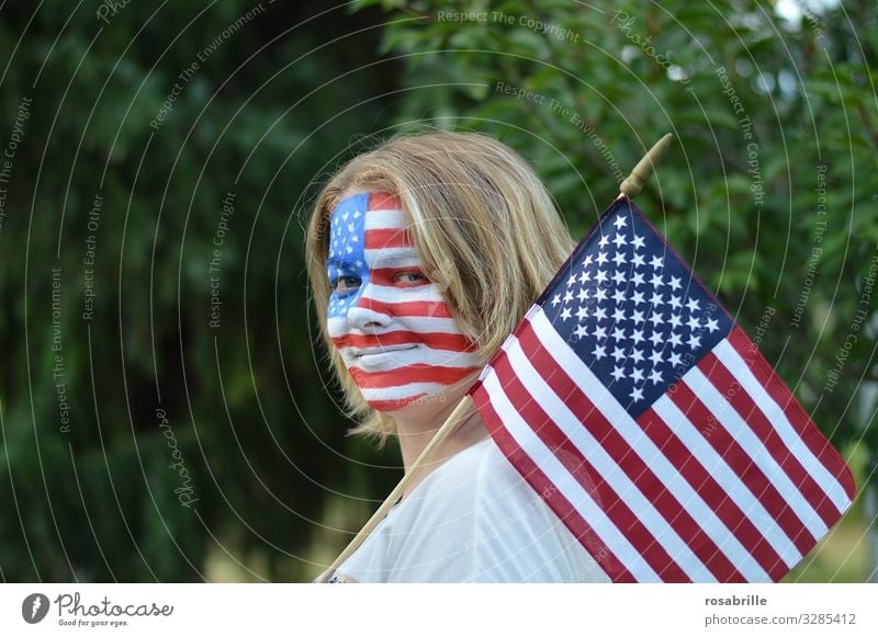 Showing the flag | literally | patriotic young blonde woman with American flag and flag painted on her face outdoors hoping for the victory of her soccer team