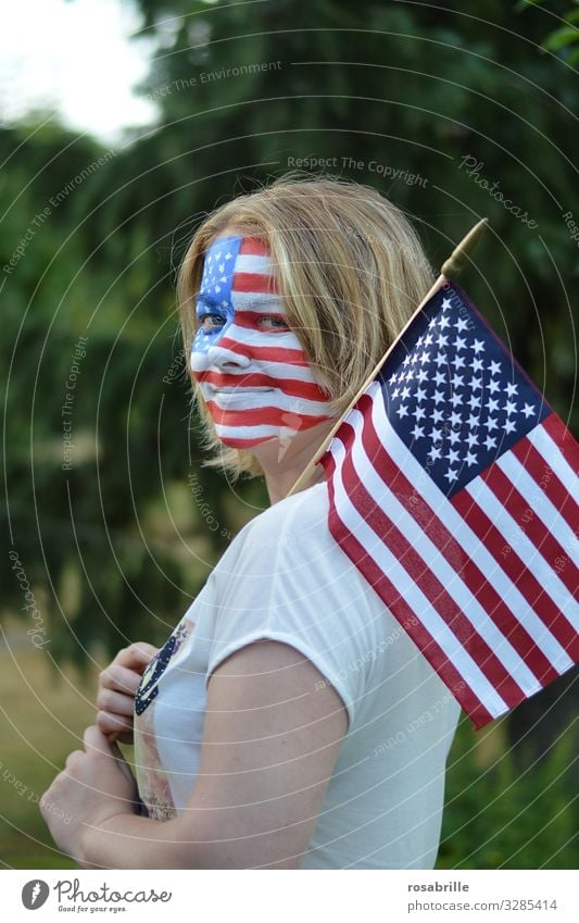 Show your colours | literally | patriotic young blonde woman with American flag and banner painted on her face outdoors hoping for the victory of her soccer team