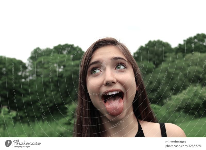 young woman in a park with open mouth and tongue out Lifestyle Beautiful Young woman Youth (Young adults) Woman Adults 13 - 18 years 18 - 30 years Laughter
