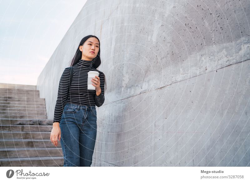 Asian woman holding a cup of coffee. Drinking Coffee Lifestyle Style Happy Beautiful Profession Human being Woman Adults Street Brunette Going Smiling Modern
