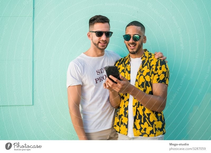 Gay couple spending time together while using phone. Lifestyle Happy Leisure and hobbies Freedom Cellphone PDA Homosexual Man Adults Couple Love Happiness