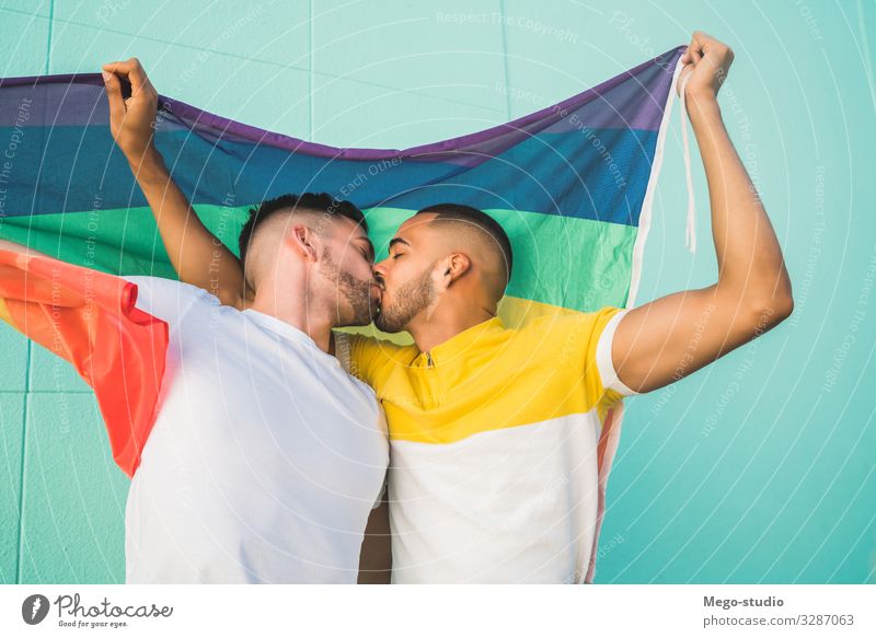 Gay couple embracing and showing their love with rainbow flag. Lifestyle Happy Freedom Feasts & Celebrations Human being Homosexual Man Adults Couple Partner