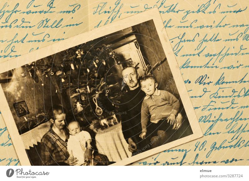 an old paper painting from the 1920s shows a family with two small children in front of a decorated Christmas tree - lying on an old document in old German handwriting